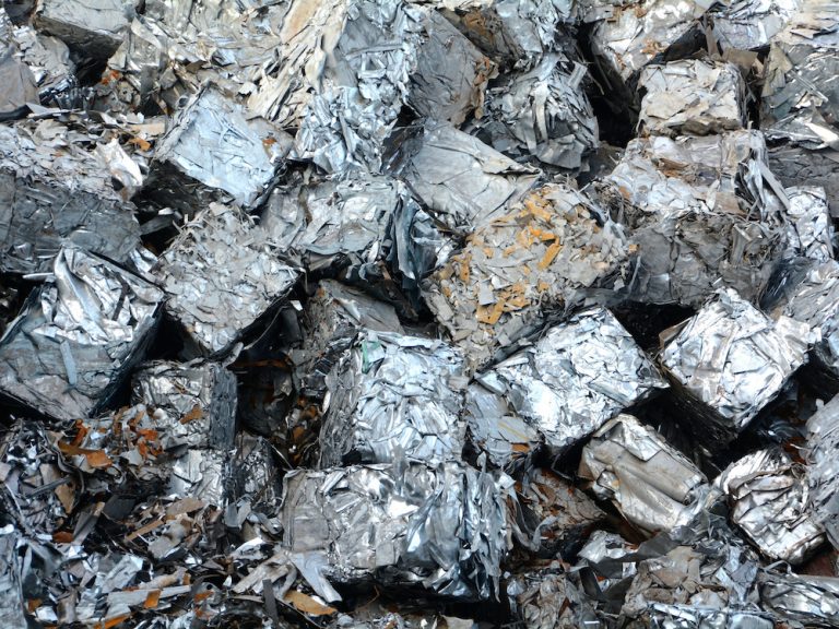 bales of compressed scrap metal sit in a big pile, waiting to be processed