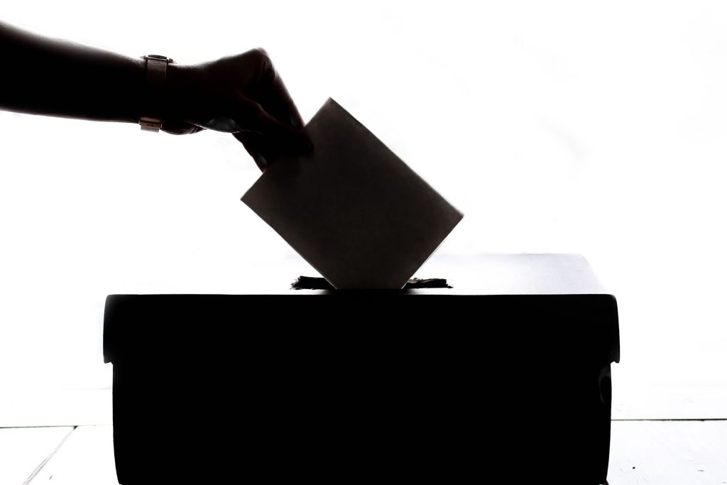 A person drops a folded ballot into a box