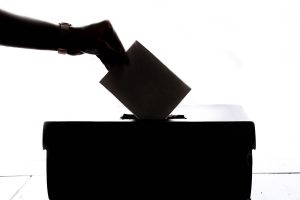 A person drops a folded ballot into a box